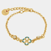 Bracciale in metallo con finitura dorata del marchio BySimon appartenente alla collezione Fiori di Lava caratterizzato da un design mediterraneo con maglia a catena rolo. Il gioiello presenta un elemento centrale a forma di quadrifoglio traforato ispirato alle maioliche siciliane, decorato con smalto azzurro sui petali e un motivo a rilievo dorato nel mezzo. Ai lati del decoro centrale sono incastonate due piccole perle bianche circondate da una lavorazione granulata. Completano il bracciale una chiusura a 