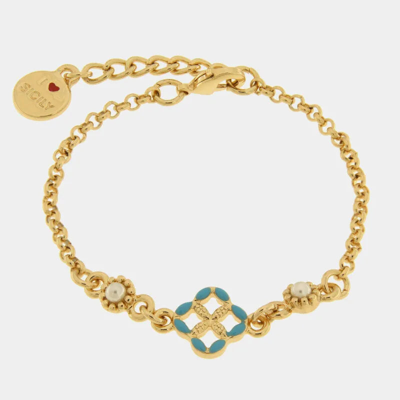 Bracciale in metallo con finitura dorata del marchio BySimon appartenente alla collezione Fiori di Lava caratterizzato da un design mediterraneo con maglia a catena rolo. Il gioiello presenta un elemento centrale a forma di quadrifoglio traforato ispirato alle maioliche siciliane, decorato con smalto azzurro sui petali e un motivo a rilievo dorato nel mezzo. Ai lati del decoro centrale sono incastonate due piccole perle bianche circondate da una lavorazione granulata. Completano il bracciale una chiusura a 
