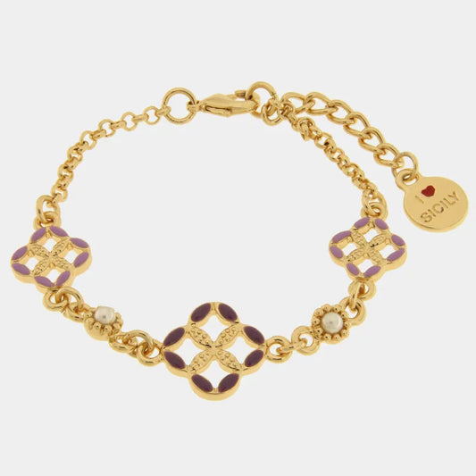 
Bracciale in metallo con finitura dorata del marchio BySimon appartenente alla collezione Fiori di Lava caratterizzato da una maglia a catena rolo impreziosita da tre elementi a forma di quadrifoglio traforato. Il charm centrale presenta petali rifiniti in smalto viola scuro, mentre i due charms laterali sono decorati con smalto lilla e alternati a due piccole perle bianche incastonate in una cornice lavorata a rilievo. Il gioiello include una chiusura con moschettone, una catenella di estensione per regol