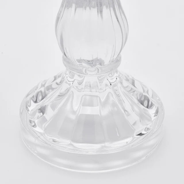 Candelabro in vetro trasparente modello Crystal firmato EDG Enzo de Gasperi, caratterizzato da un'elegante struttura classica con fusto sinuoso e scanalature verticali riflettenti. Questo raffinato portacandele di design presenta una base circolare lavorata, ideale come centrotavola decorativo per illuminare e impreziosire gli ambienti di casa.