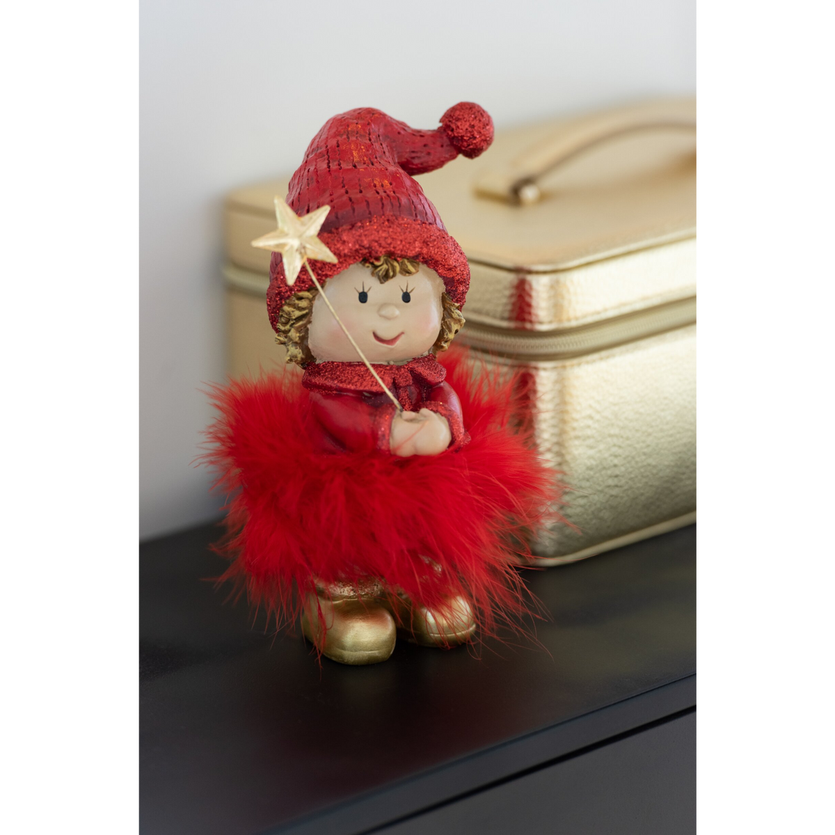 Statuina natalizia di bambino con berretto glitterato rosso, gonna di piume e stivaletti dorati, con bacchetta a forma di stella. Decorazione assortita in due modelli, ideale per l'home décor e come idea regalo.