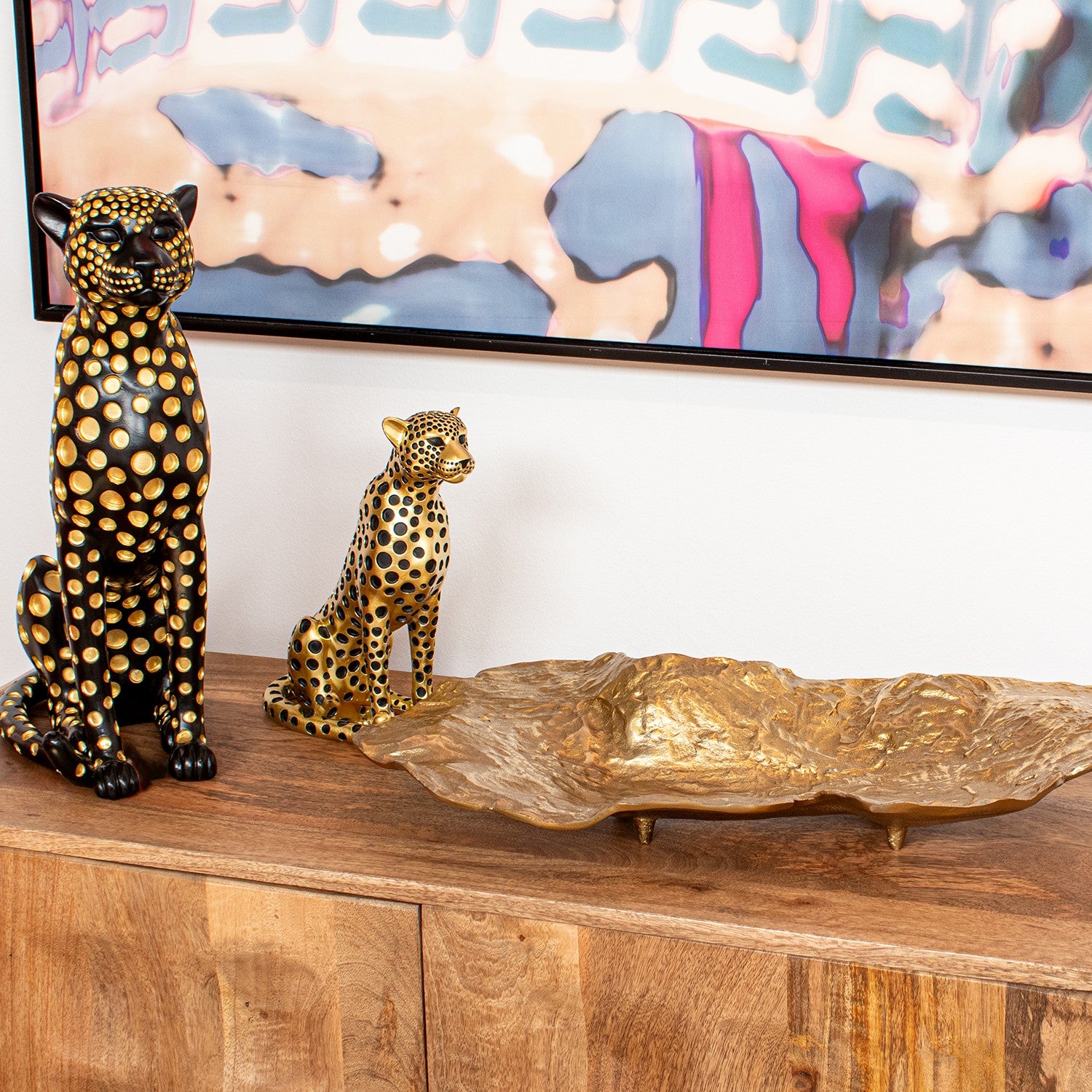 Figura in resina di leopardo nero e oro firmata e-camacho, raffigurante un ghepardo seduto di profilo con un design moderno ricoperto da pois dorati a rilievo. Questa statuina decorativa e scultura da collezione rappresenta un soprammobile di lusso ideale per l'arredamento d'interni elegante e di design.