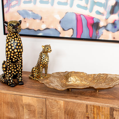 Figura in resina di leopardo nero e oro firmata e-camacho, raffigurante un ghepardo seduto di profilo con un design moderno ricoperto da pois dorati a rilievo. Questa statuina decorativa e scultura da collezione rappresenta un soprammobile di lusso ideale per l'arredamento d'interni elegante e di design.