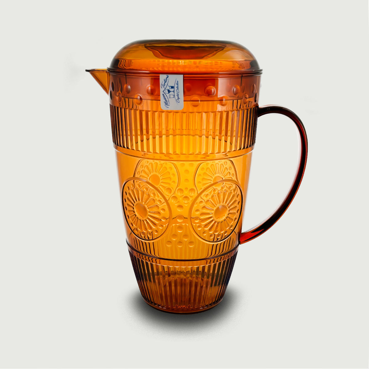 Una caraffa in plastica dal colore ambra trasparente, caratterizzata da una raffinata lavorazione a rilievo floreale e righe verticali che ne movimentano la superficie, richiamando lo stile del cristallo lavorato. Dotata di beccuccio versatore, coperchio e comoda manico ad ansa, unisce estetica vintage e praticità d'uso. Un accessorio dal gusto elegante e colorato, perfetto per la tavola estiva o per servire bevande fresche con stile.