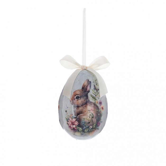 Decorazione pasquale Blanc Mariclò a forma di uovo carta da zucchero con nastro in raso avorio. Il decoro centrale in stile vintage raffigura un coniglietto bianco seduto tra dei fiori.