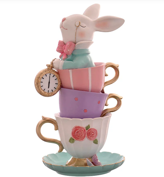 Statuina decorativa in resina raffigurante un coniglio bianco in stile Alice nel Paese delle Meraviglie, seduto all'interno di una pila di tre tazzine da tè multicolor (rosa, lilla e bianca con rose). Il coniglio indossa una giacca azzurra, un papillon rosa e un monocolo, mentre tiene in mano un orologio da taschino dorato. Base a forma di piattino verde acqua con bordi dorati.