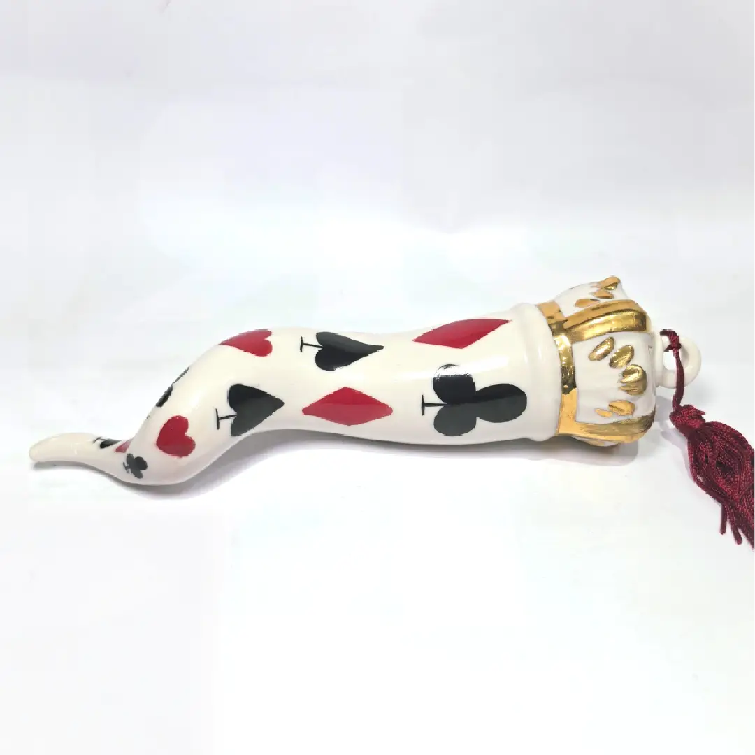 Corno portafortuna in ceramica bianca lucida decorato con i semi delle carte da gioco neri e rossi, completato da una corona regale bianca e oro con nappa coordinata. Questo raffinato oggetto scaramantico di design artigianale è un complemento d'arredo originale e scaramantico, perfetto come idea regalo o per decorare ambienti moderni con un tocco di tradizione napoletana.