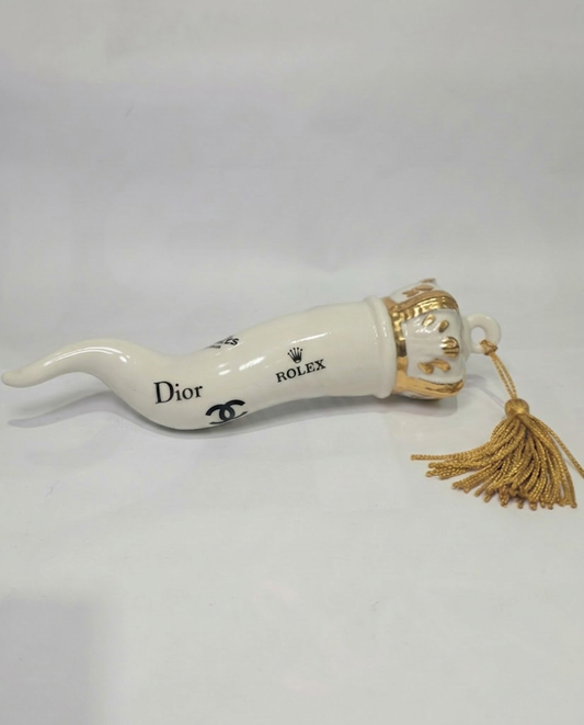 Corno portafortuna in ceramica bianca lucida decorato con loghi fashion neri e completato da una corona regale dorata con nappa in seta oro. Questo elegante oggetto scaramantico di design artigianale rappresenta un complemento d'arredo pop lussuoso e originale, perfetto come idea regalo o decorazione d'interni moderna.