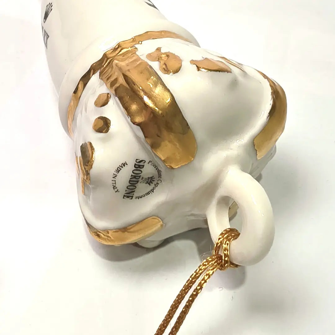 Corno portafortuna in ceramica bianca lucida decorato con loghi fashion neri e completato da una corona regale dorata con nappa in seta oro. Questo elegante oggetto scaramantico di design artigianale rappresenta un complemento d'arredo pop lussuoso e originale, perfetto come idea regalo o decorazione d'interni moderna.