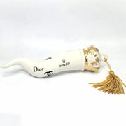 Corno portafortuna in ceramica bianca lucida decorato con loghi fashion neri e completato da una corona regale dorata con nappa in seta oro. Questo elegante oggetto scaramantico di design artigianale rappresenta un complemento d'arredo pop lussuoso e originale, perfetto come idea regalo o decorazione d'interni moderna.