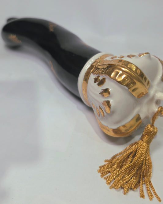 Corno portafortuna in ceramica nera lucida decorato con loghi fashion dorati e completato da una corona regale dorata con nappa in seta oro. Questo elegante oggetto scaramantico di design artigianale rappresenta un complemento d'arredo pop lussuoso e originale, perfetto come idea regalo o decorazione d'interni moderna.
