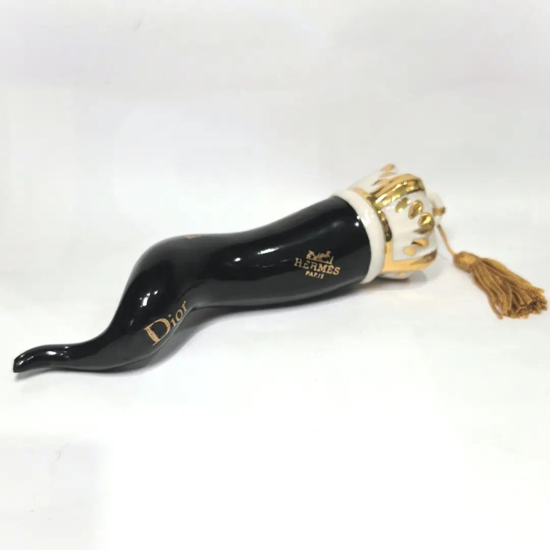 Corno portafortuna in ceramica nera lucida decorato con loghi fashion dorati e completato da una corona regale dorata con nappa in seta oro. Questo elegante oggetto scaramantico di design artigianale rappresenta un complemento d'arredo pop lussuoso e originale, perfetto come idea regalo o decorazione d'interni moderna.