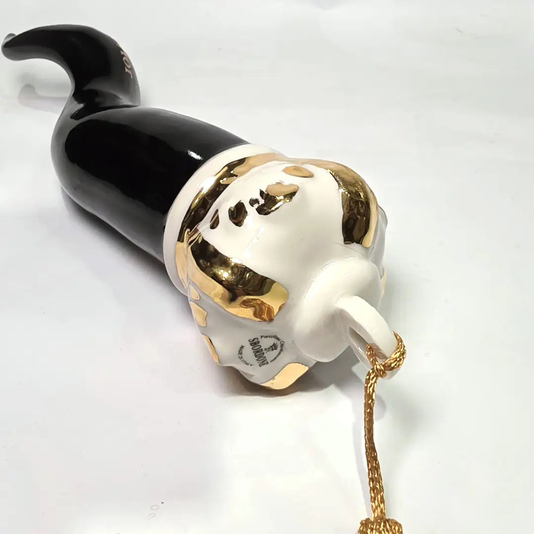 Corno portafortuna in ceramica nera lucida decorato con loghi fashion dorati e completato da una corona regale dorata con nappa in seta oro. Questo elegante oggetto scaramantico di design artigianale rappresenta un complemento d'arredo pop lussuoso e originale, perfetto come idea regalo o decorazione d'interni moderna.