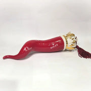 Corno portafortuna in ceramica rossa lucida decorato con loghi fashion bianchi e completato da una corona regale dorata con nappa in seta rossa. Questo elegante oggetto scaramantico di design artigianale rappresenta un complemento d'arredo pop lussuoso e originale, perfetto come idea regalo o decorazione d'interni moderna.
