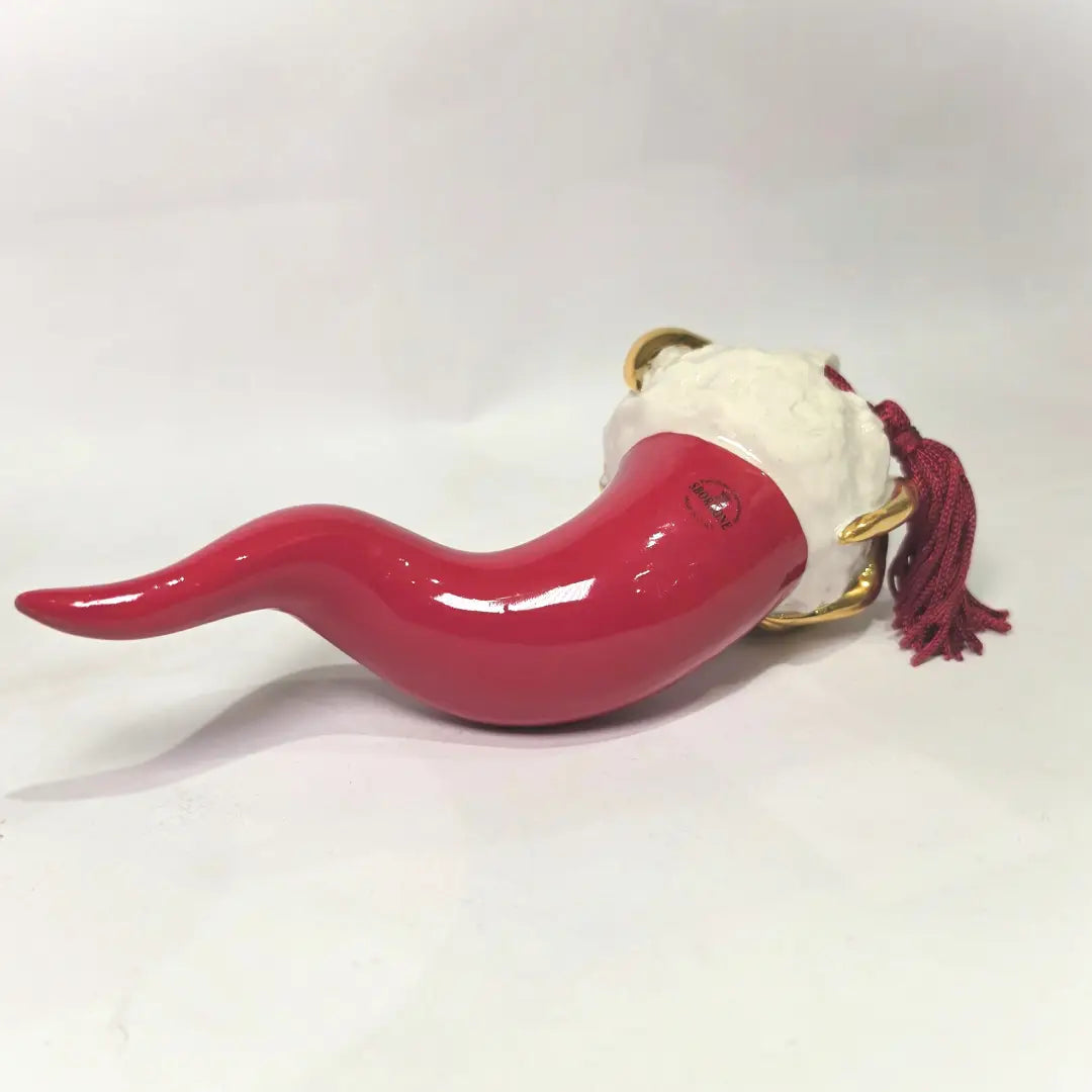 Corno portafortuna in ceramica rossa lucida di manifattura artigianale, caratterizzato da una punta ricurva e una corona regale dorata posta sulla sommità. Questo amuleto scaramantico dal design classico è un complemento d'arredo elegante, ideale come regalo di buon augurio o per decorare ambienti con un tocco di tradizione mediterranea.