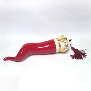 Corno portafortuna in ceramica rossa lucida caratterizzato da una corona regale bianca con decorazioni dorate e una nappa in tessuto rosso coordinata. Questo raffinato amuleto scaramantico dal design artigianale è un complemento d'arredo perfetto per decorare la casa con stile e tradizione.