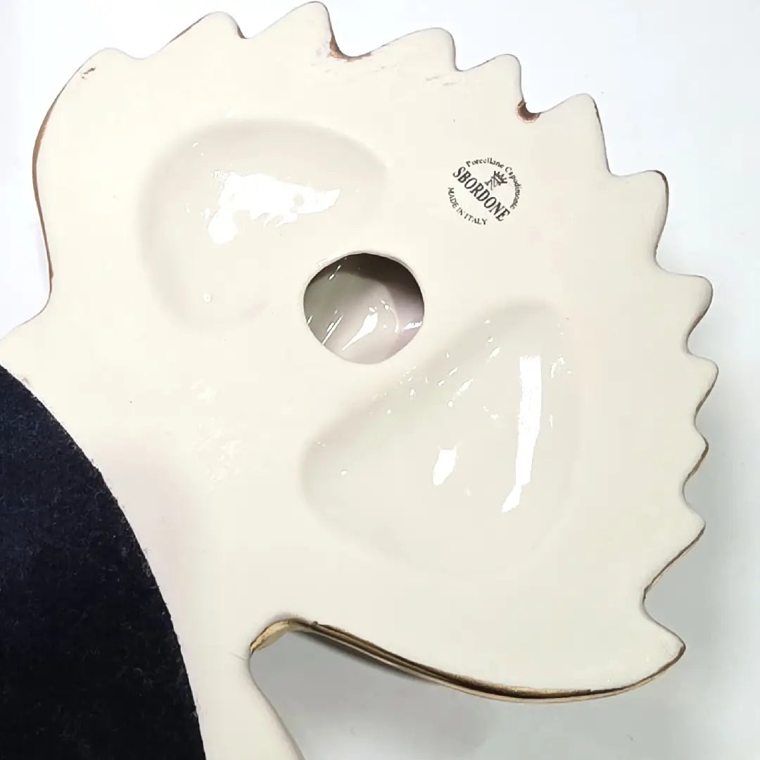 Scultura da parete a forma di Cuore Sacro grande in ceramica rossa lucida, decorata con diversi loghi fashion bianchi e sormontata da una fiamma dorata a rilievo. L'oggetto è rifinito con una cornice perlinata bianca e borchie oro, rappresentando un complemento d'arredo pop art dal design audace ideale per ambienti moderni.