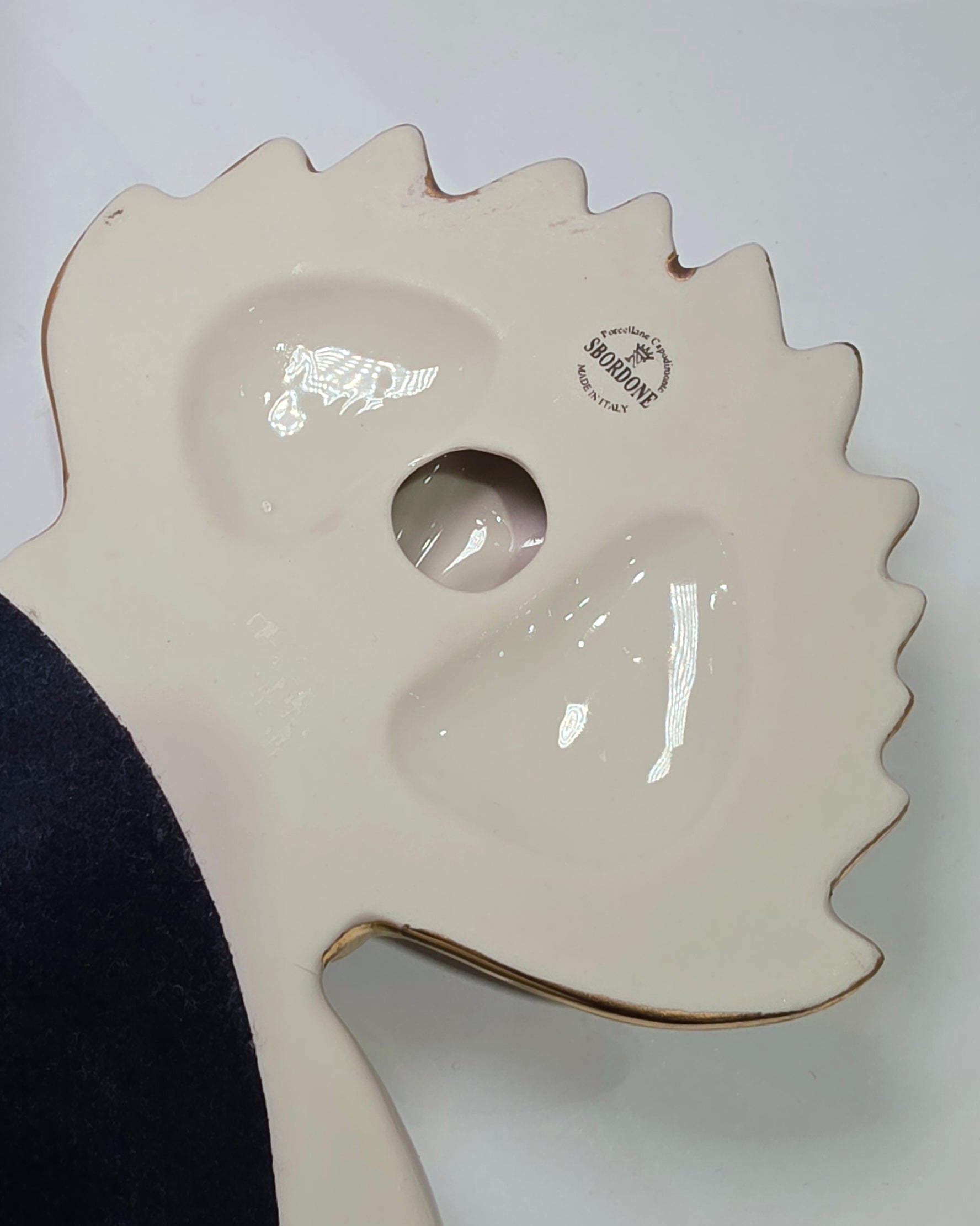 Scultura da parete a forma di Cuore Sacro grande in ceramica rossa lucida, decorata con diversi loghi fashion bianchi e sormontata da una fiamma dorata a rilievo. L'oggetto è rifinito con una cornice perlinata bianca e borchie oro, rappresentando un complemento d'arredo pop art dal design audace ideale per ambienti moderni.