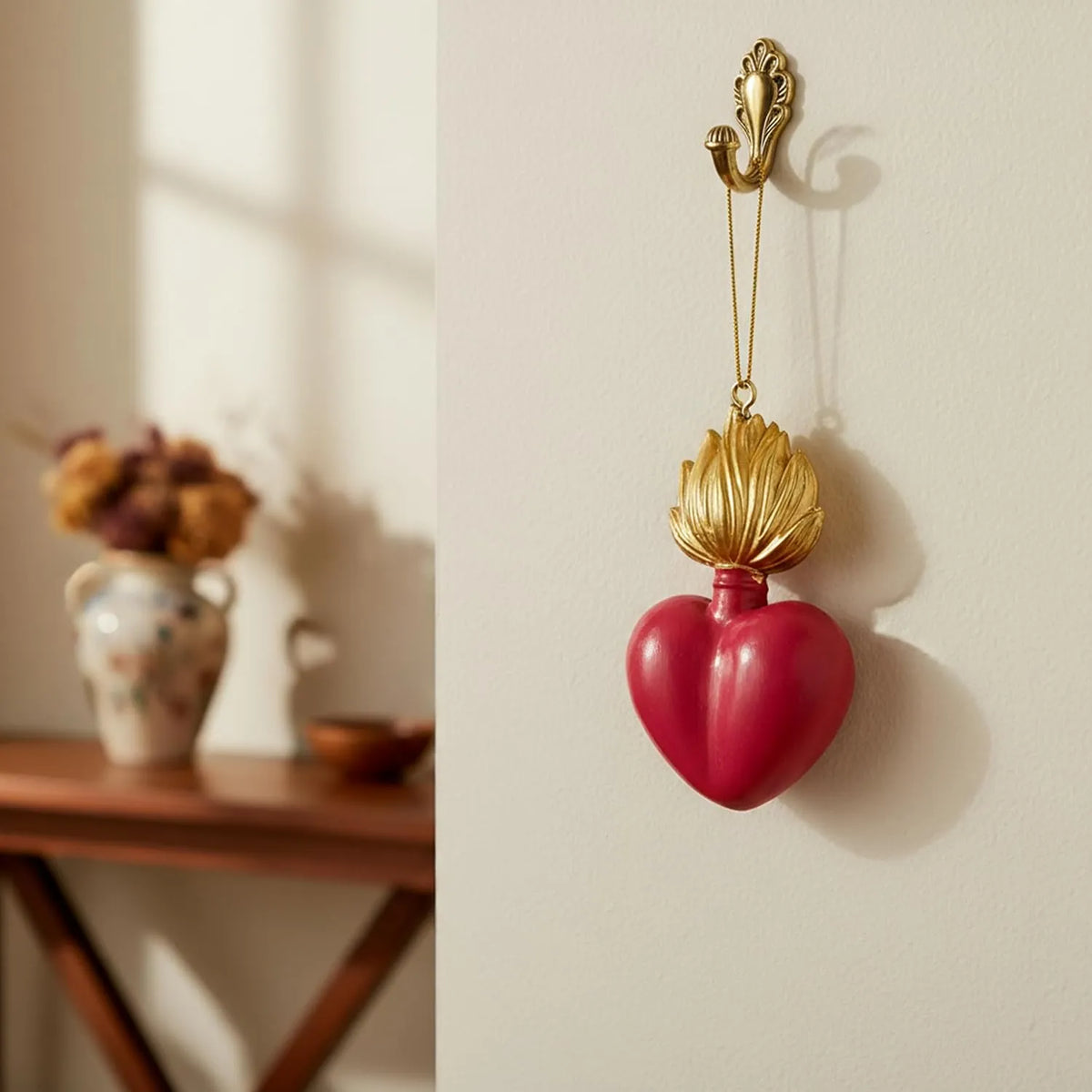 Ciondolo decorativo a forma di cuore sacro votivo, con fiamma dorata superiore, centro smaltato fucisa e nastro dorato per appenderlo, misure 9x5.5 cm. Decoro portafortuna artigianale firmato Montemaggi, ideale come ornamento per l'albero o idea regalo originale.