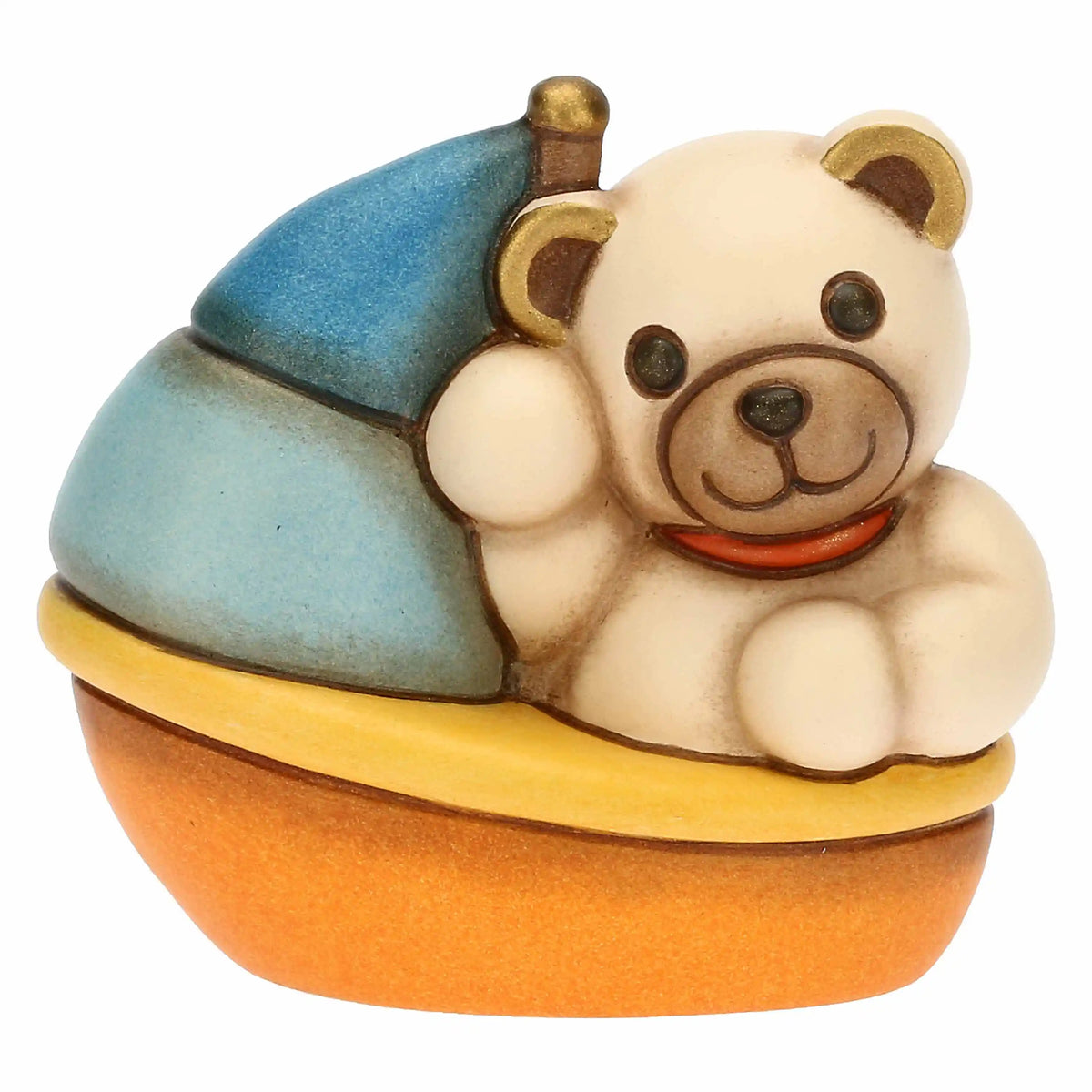 Statuina in ceramica raffigurante un orsetto teddy seduto su una barchetta azzurra, gialla e arancio con vela blu e camino dorato. Decorazione dipinta a mano, ideale per la cameretta e come idea regalo.