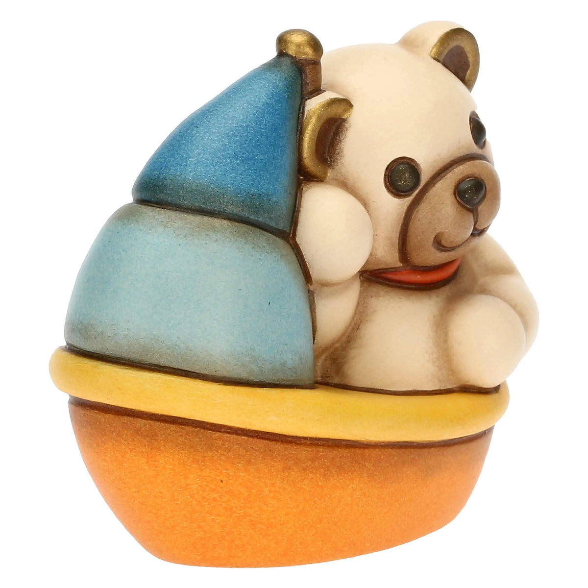 Statuina in ceramica raffigurante un orsetto teddy seduto su una barchetta azzurra, gialla e arancio con vela blu e camino dorato. Decorazione dipinta a mano, ideale per la cameretta e come idea regalo.