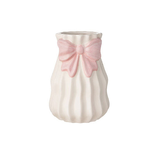 Vaso alto in ceramica bianca del marchio L'arte dei nacchi caratterizzato da una superficie con lavorazione a costine verticali ondulate che donano movimento al design. Il complemento d'arredo è impreziosito da un fiocco rosa decorativo in rilievo applicato sulla parte superiore vicino all'apertura, ideale come bomboniera o elemento decorativo per la casa dallo stile romantico e delicato.