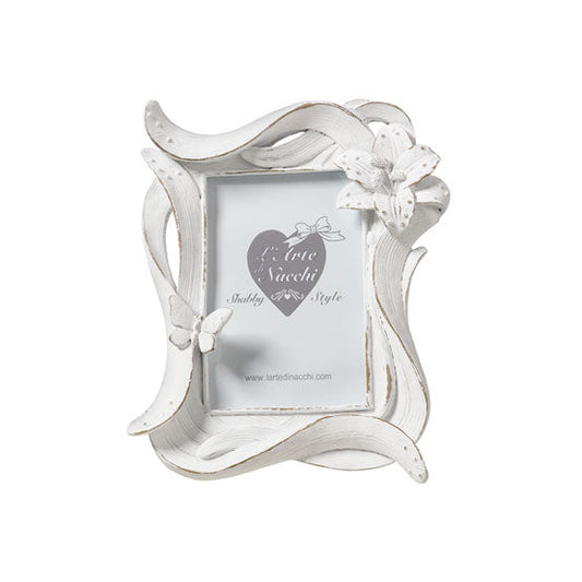 
Cornice portafoto del marchio L'arte dei nacchi realizzata in resina bianca con una particolare lavorazione dinamica a onde ed effetto decapato tipico dello stile shabby chic. Il design è impreziosito da un fiore tridimensionale in rilievo posizionato sull'angolo superiore destro e da una piccola farfalla coordinata applicata sul lato sinistro della cornice. Questo portafoto decorativo è ideale per personalizzare l'arredamento di camere e soggiorni o come bomboniera ricercata per cerimonie e ricorrenze spe