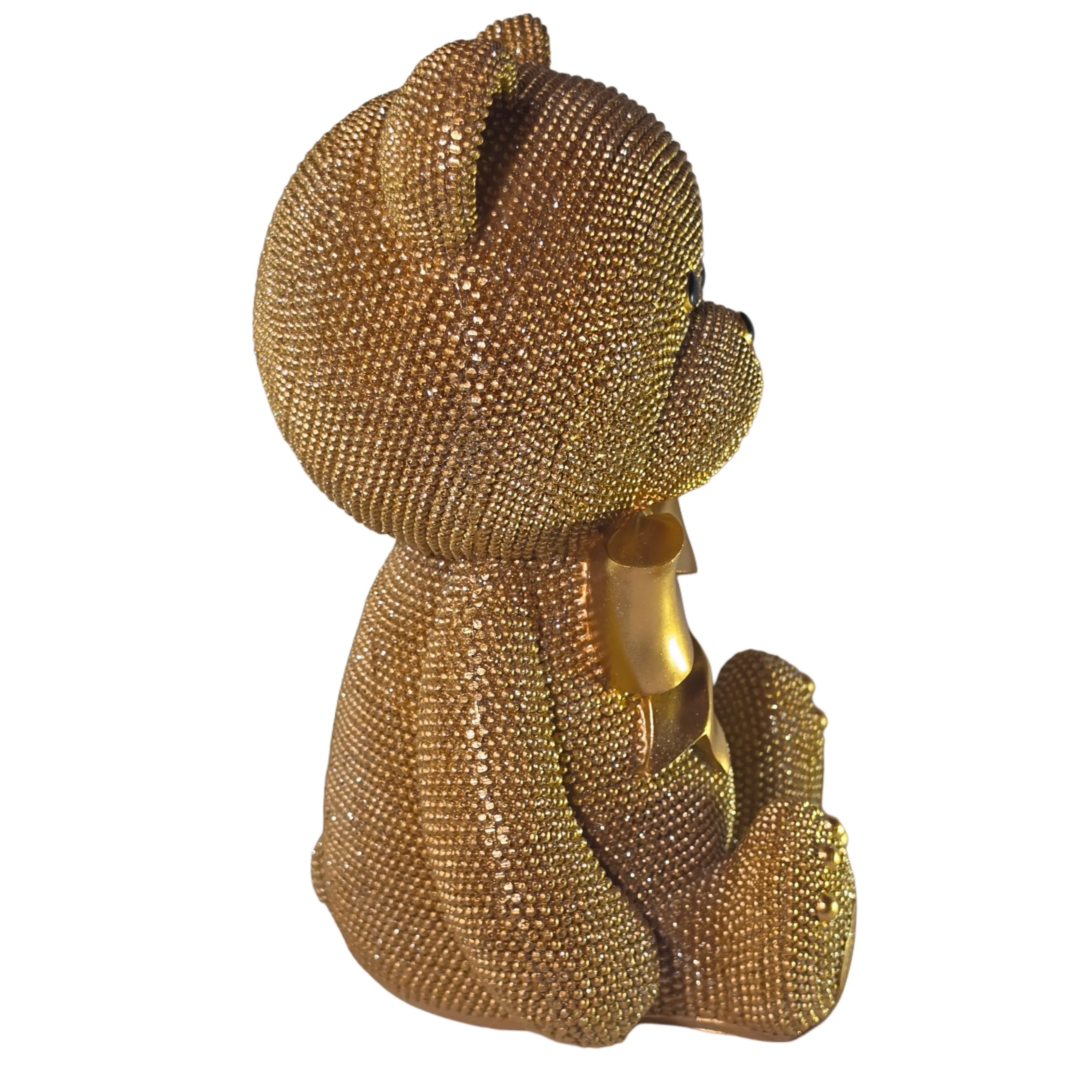 Statuina orsetto in resina dorata interamente ricoperta di brillantini glitterati, con fiocco raso oro al collo, occhi e naso neri e cuciture in rilievo sulle zampe. Oggetto decorativo scintillante firmato Sud Import, ideale come soprammobile glamour o idea regalo per bambini e occasioni speciali.