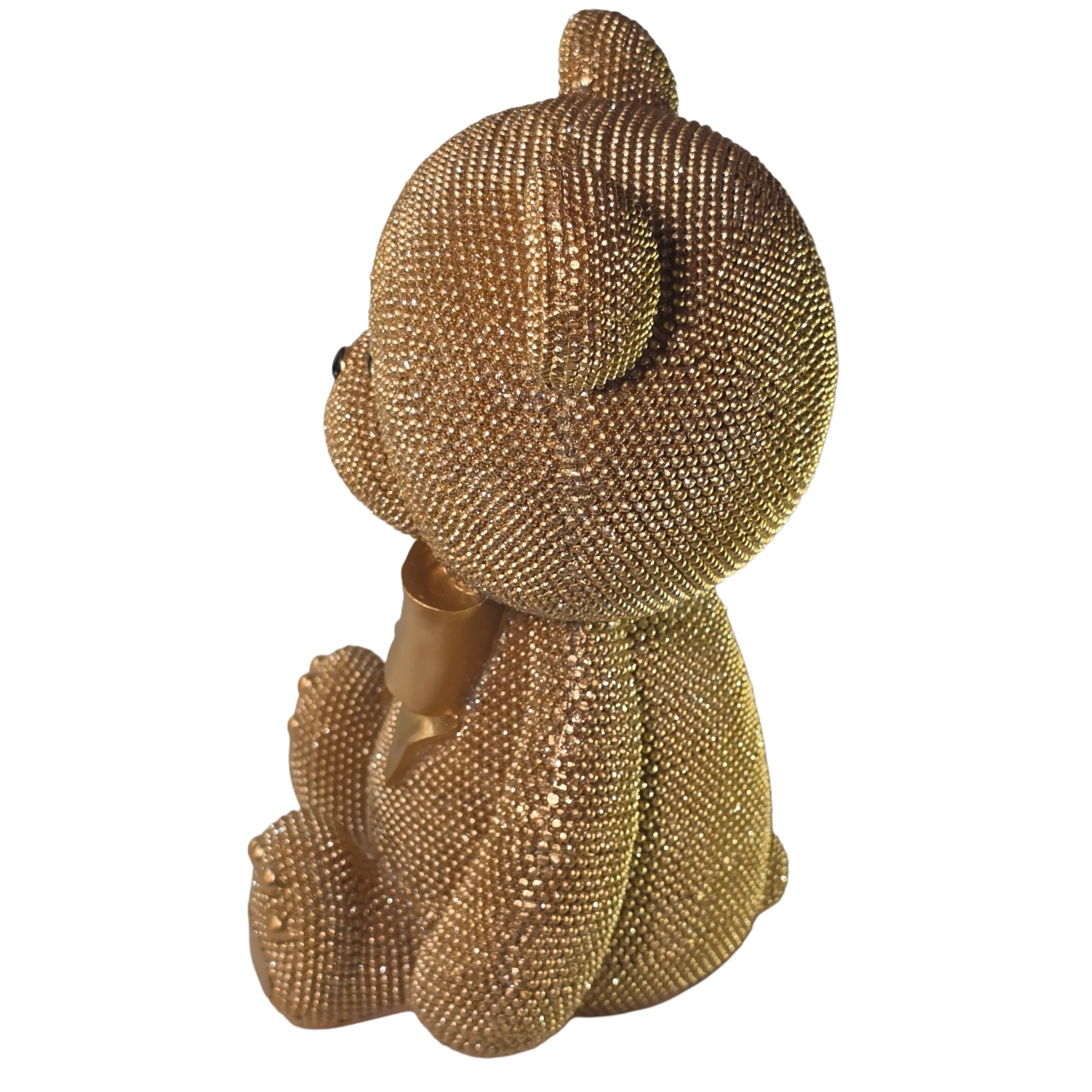 Statuina orsetto in resina dorata interamente ricoperta di brillantini glitterati, con fiocco raso oro al collo, occhi e naso neri e cuciture in rilievo sulle zampe. Oggetto decorativo scintillante firmato Sud Import, ideale come soprammobile glamour o idea regalo per bambini e occasioni speciali.