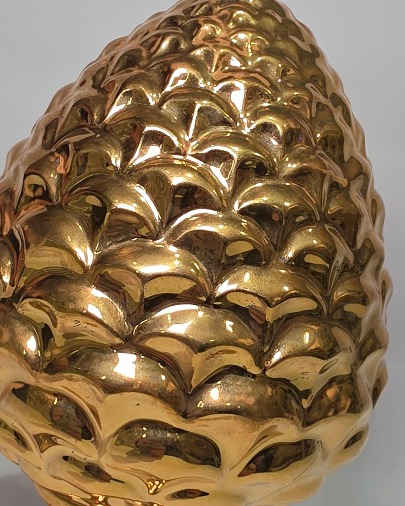 Pigna portafortuna in ceramica dorata lucida di manifattura artigianale, caratterizzata da squame finemente modellate e una solida base d'appoggio coordinata. Questo raffinato oggetto ornamentale rappresenta un simbolo di prosperità e accoglienza, perfetto come complemento d'arredo di lusso per interni classici o moderni.