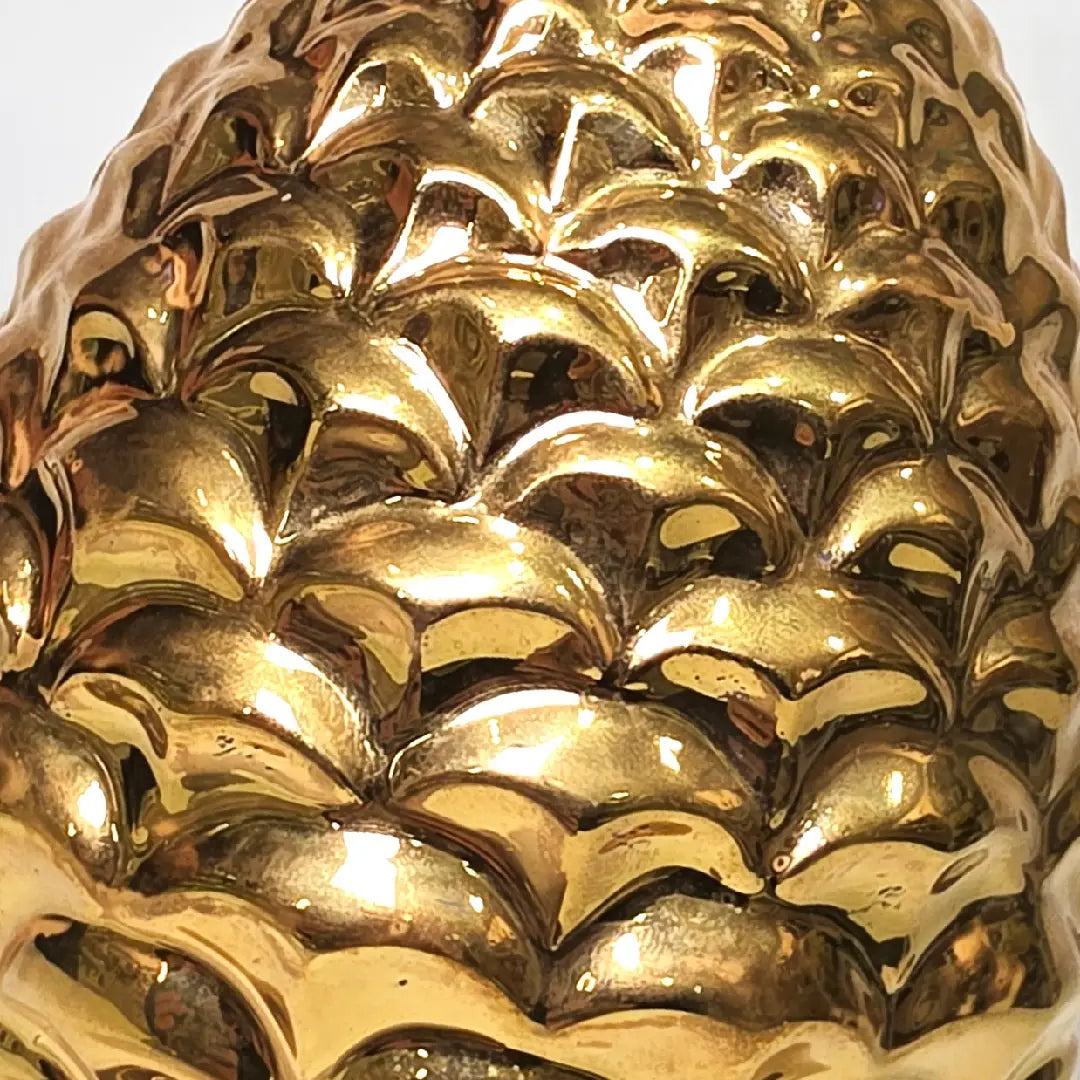 Pigna portafortuna in ceramica dorata lucida di manifattura artigianale, caratterizzata da squame finemente modellate e una solida base d'appoggio coordinata. Questo raffinato oggetto ornamentale rappresenta un simbolo di prosperità e accoglienza, perfetto come complemento d'arredo di lusso per interni classici o moderni.