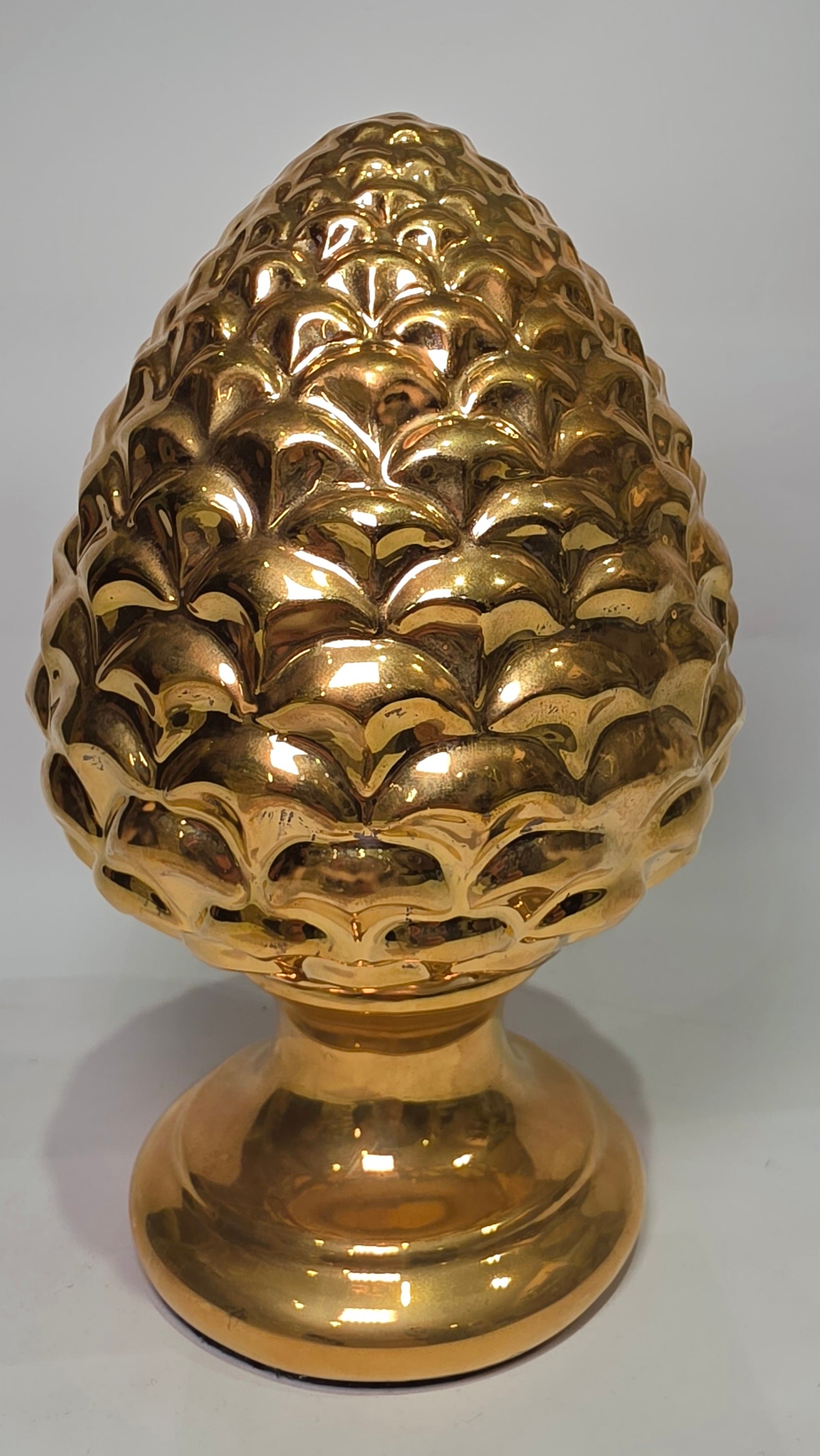 Pigna portafortuna in ceramica dorata lucida di manifattura artigianale, caratterizzata da squame finemente modellate e una solida base d'appoggio coordinata. Questo raffinato oggetto ornamentale rappresenta un simbolo di prosperità e accoglienza, perfetto come complemento d'arredo di lusso per interni classici o moderni.