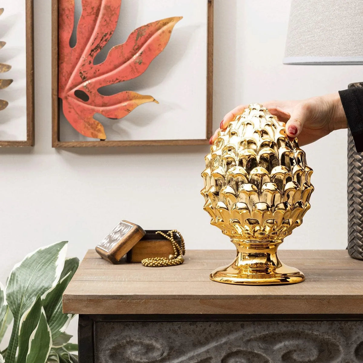 Pigna decorativa in ceramica dorata dalla tipica forma siciliana, con superficie lucida a squame in rilievo e base tornita. Oggetto d'arredo dalla tradizione mediterranea firmato Montemaggi, ideale come soprammobile o idea regalo raffinata.