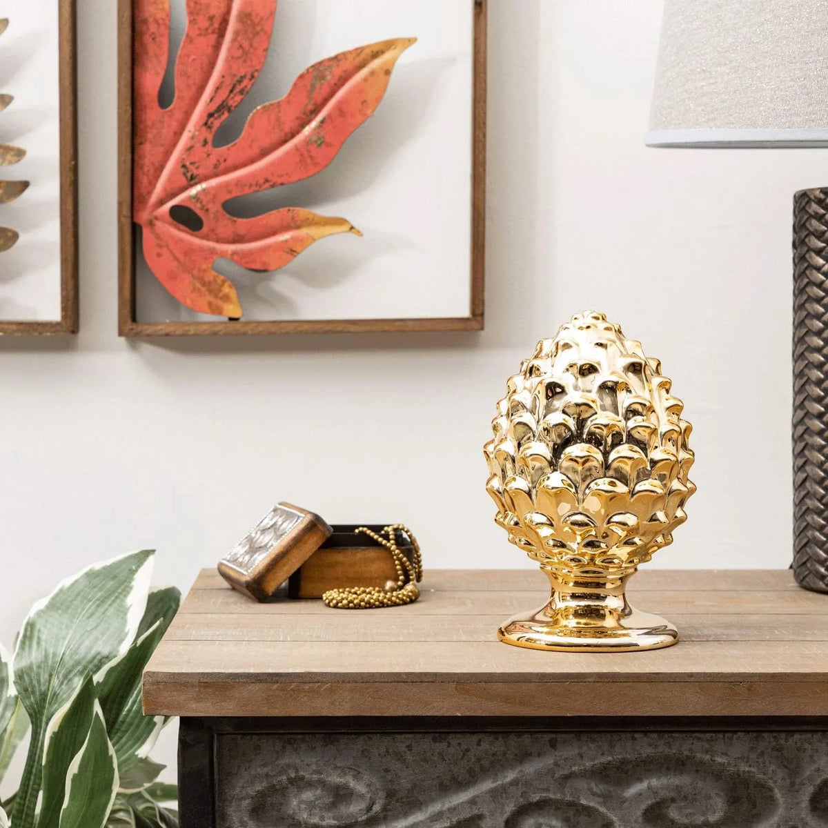 Pigna decorativa in ceramica dorata dalla tipica forma siciliana, con superficie lucida a squame in rilievo e base tornita. Oggetto d'arredo dalla tradizione mediterranea firmato Montemaggi, ideale come soprammobile o idea regalo raffinata.