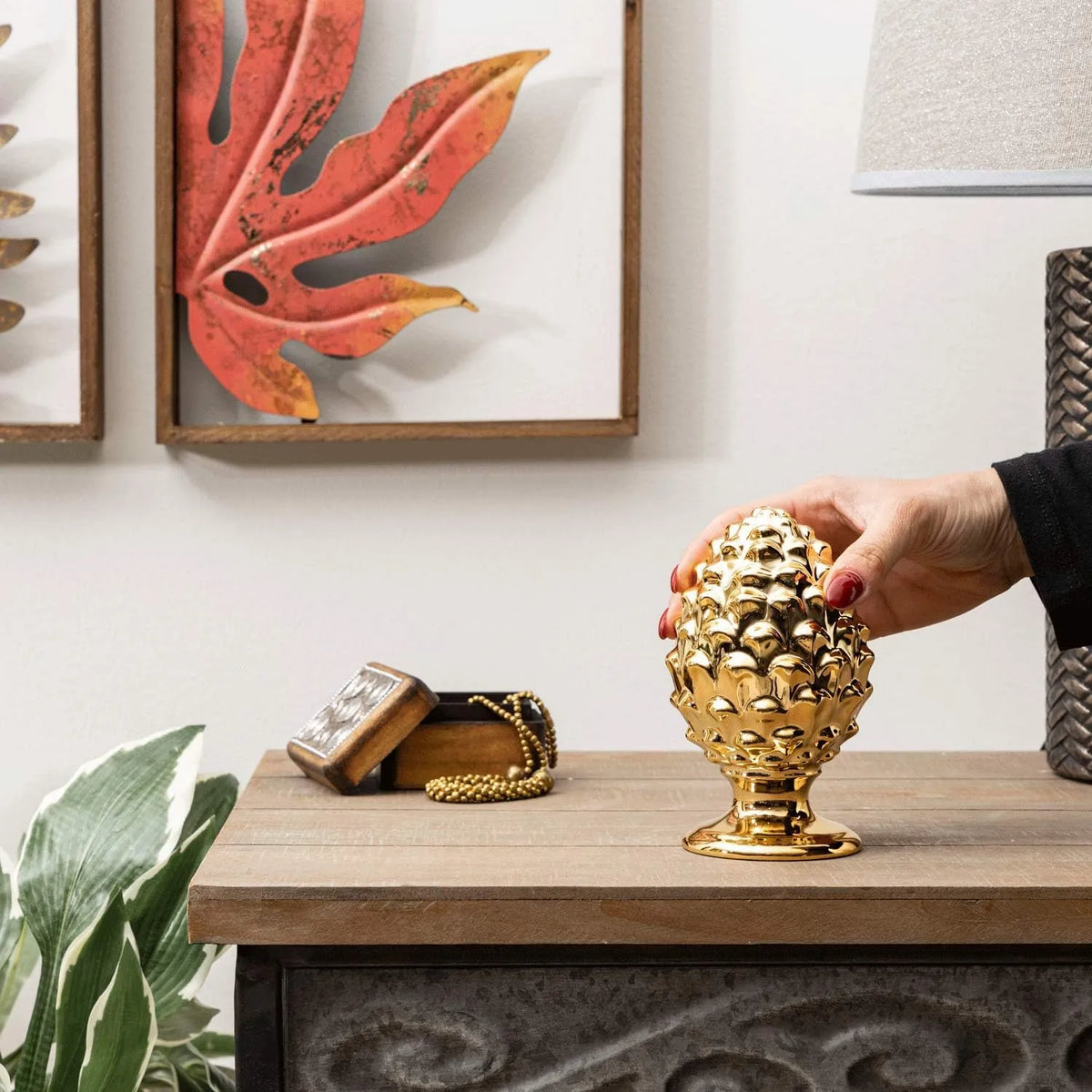 Pigna decorativa in ceramica dorata dalla tipica forma siciliana, con superficie lucida a squame in rilievo e base tornita. Oggetto d'arredo dalla tradizione mediterranea firmato Montemaggi, ideale come soprammobile o idea regalo raffinata.