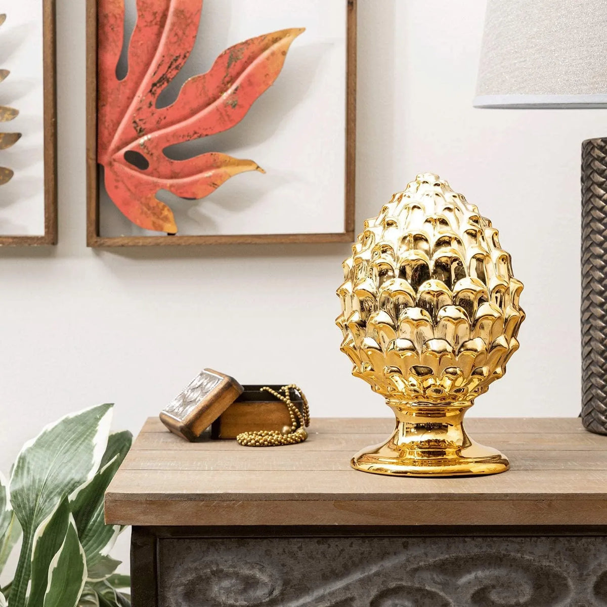 Pigna decorativa in ceramica dorata dalla tipica forma siciliana, con superficie lucida a squame in rilievo e base tornita. Oggetto d'arredo dalla tradizione mediterranea firmato Montemaggi, ideale come soprammobile o idea regalo raffinata.