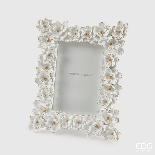 Elegante portafoto in resina bianca firmato EDG Enzo De Gasperi caratterizzato da una ricca cornice interamente decorata con fiori tridimensionali in rilievo dai bordi dorati. Questa cornice portafoto floreale dal design romantico è un raffinato complemento d'arredo ideale per impreziosire ambienti classici o come preziosa idea regalo. Grazie alla cura artigianale dei dettagli e alla finitura luminosa, il portafoto EDG valorizza ogni immagine trasformandola in un oggetto decorativo unico.