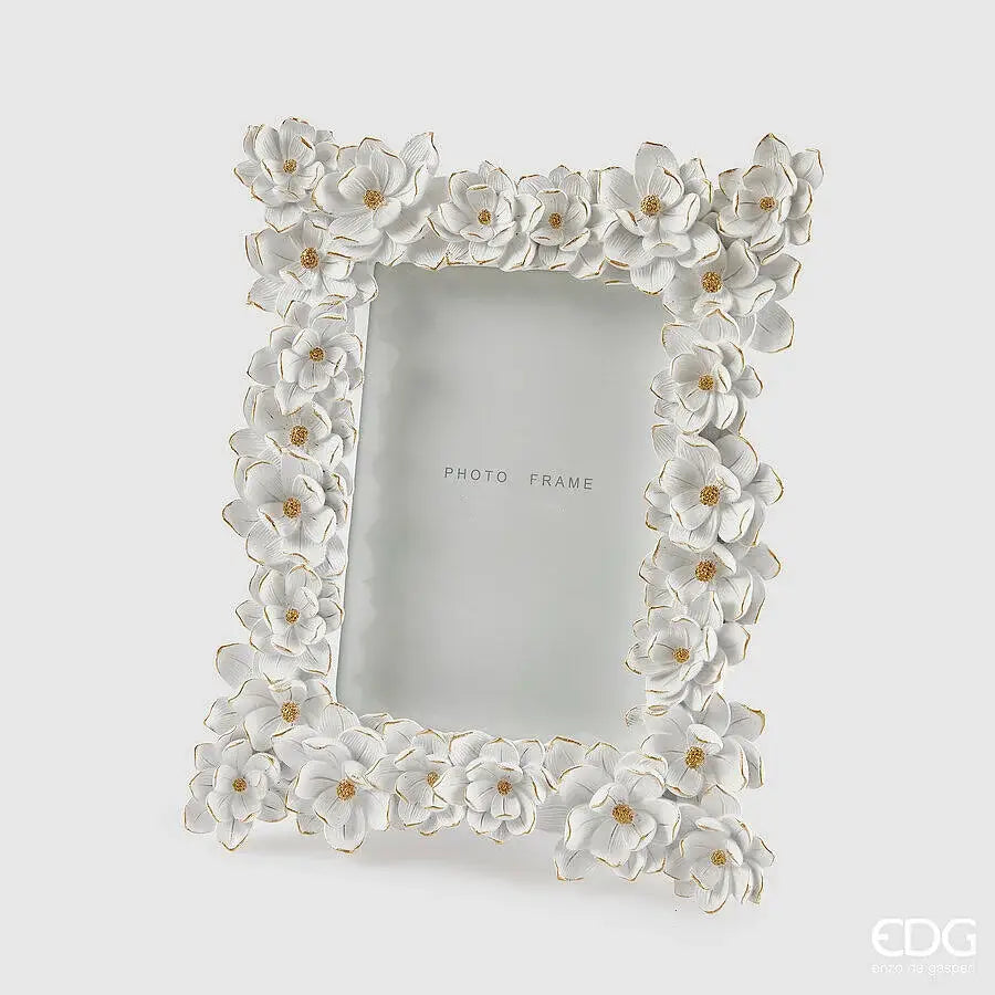 Elegante portafoto in resina bianca firmato EDG Enzo De Gasperi caratterizzato da una ricca cornice interamente decorata con fiori tridimensionali in rilievo dai bordi dorati. Questa cornice portafoto floreale dal design romantico è un raffinato complemento d'arredo ideale per impreziosire ambienti classici o come preziosa idea regalo. Grazie alla cura artigianale dei dettagli e alla finitura luminosa, il portafoto EDG valorizza ogni immagine trasformandola in un oggetto decorativo unico.