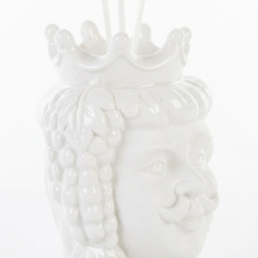 Profumatore d'ambiente in ceramica bianca lucida raffigurante una testa di moro maschile con corona e baffi, decorata con grappoli d'uva e foglie in rilievo, con bastoncini bianchi e boccetta di fragranza "Home Fragrance". Diffusore dalla tradizione siciliana firmato Le Stelle, presentato con la sua confezione bianca del marchio, ideale come idea regalo raffinata.