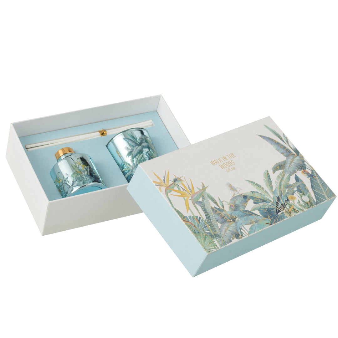 Il Set Regalo Candela e Diffusore Walk in the Woods Jolipa è un raffinato kit fragranza composto da una candela profumata e un diffusore con bastoncini in eleganti contenitori di vetro azzurro. La profumazione legnosa Woody Blush e la confezione decorata con uccellini e piante tropicali rendono questo set un perfetto complemento d'arredo o un'esclusiva idea regalo per la casa.