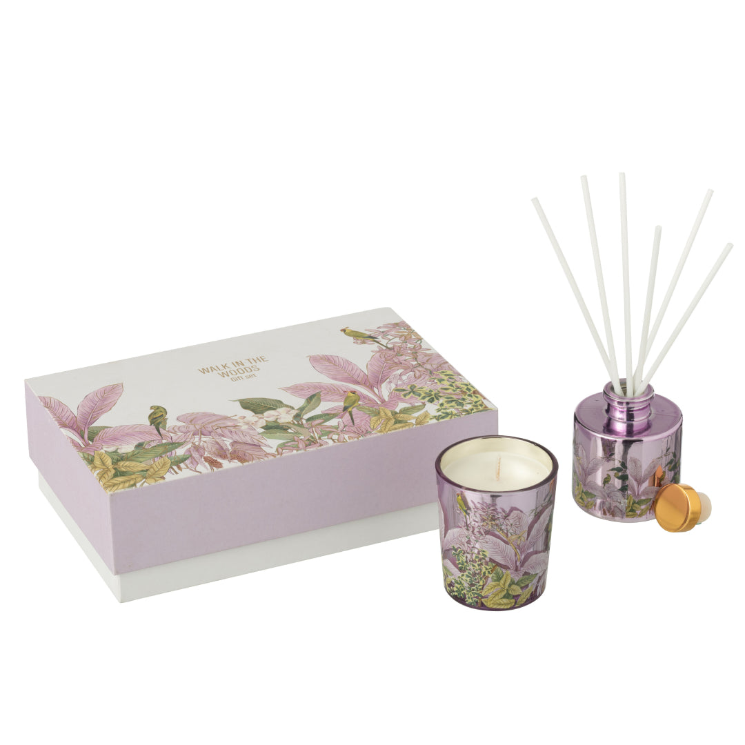 Il Set Regalo Candela e Diffusore Walk in the Woods Jolipa è un elegante cofanetto benessere che include una candela profumata e un diffusore di fragranza in vasi di vetro lilla con decorazioni botaniche. La confezione regalo raffinata con motivi di uccellini e foglie tropicali rosa rende questo kit perfetto per profumare la casa con stile o come pensiero speciale per l'home decor.