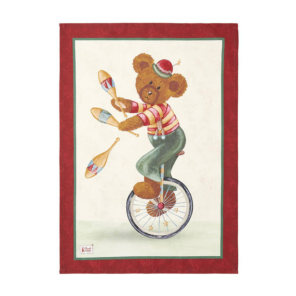 Strofinaccio natalizio in cotone Nuvole di Stoffa collezione "Bear Wonderland" (Modello C). Al centro, un orsetto acrobata su un monociclo mentre esegue un numero di giocoleria con tre clavette. Il design è incorniciato da una doppia bordatura verde e rossa su fondo panna.