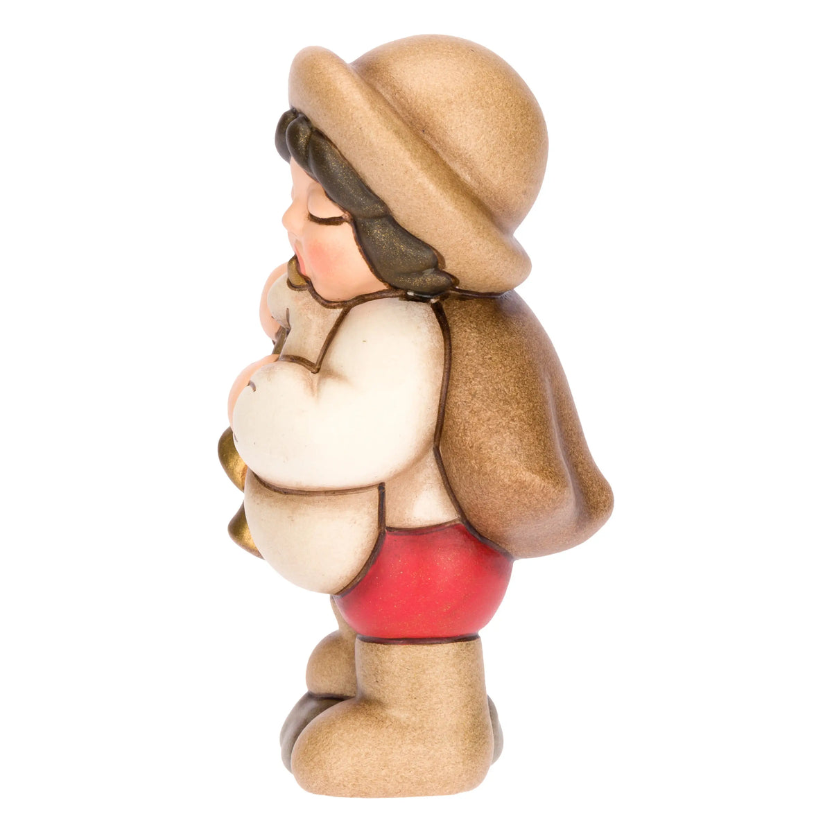 Statuina in ceramica raffigurante un piccolo zampognaro del presepe con cappello marrone e mantello, intento a suonare uno strumento a fiato dorato indossando pantaloncini rossi. Personaggio dal design classico e curato firmato THUN, ideale per arricchire il presepe o come idea regalo natalizia.