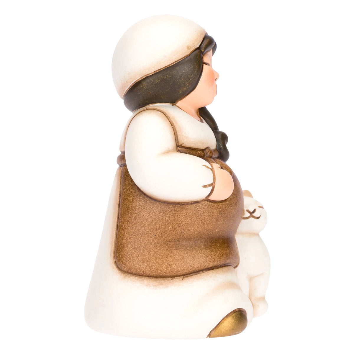 Statuina in ceramica raffigurante una pastorella del presepe in dolce attesa, con lunghi capelli scuri, veste bianca e mantello marrone, accanto a un agnellino bianco. Personaggio dal design classico e curato firmato THUN, ideale per arricchire il presepe o come idea regalo natalizia.