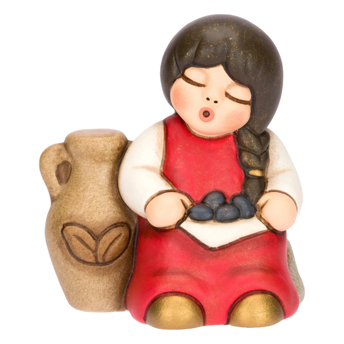 Statuina in ceramica raffigurante una bimba del presepe con treccia nera e vestito rosso e bianco, seduta accanto a un'anfora mentre raccoglie olive nel grembo. Personaggio dal design classico e curato firmato THUN, ideale per arricchire il presepe o come idea regalo natalizia.
