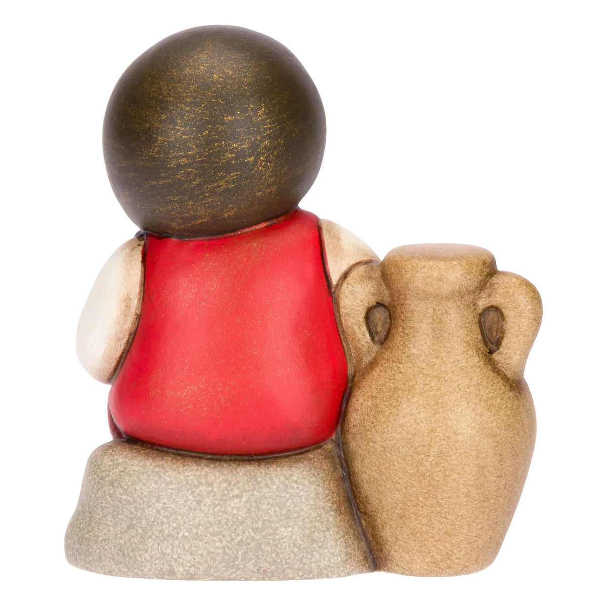 Statuina in ceramica raffigurante una bimba del presepe con treccia nera e vestito rosso e bianco, seduta accanto a un'anfora mentre raccoglie olive nel grembo. Personaggio dal design classico e curato firmato THUN, ideale per arricchire il presepe o come idea regalo natalizia.