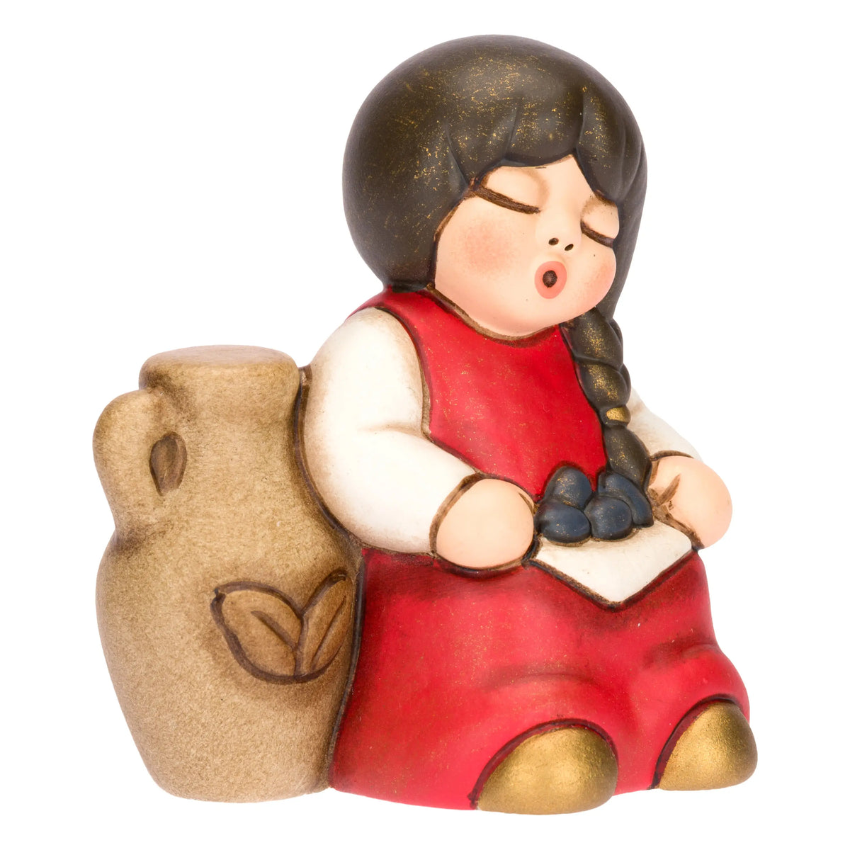 Statuina in ceramica raffigurante una bimba del presepe con treccia nera e vestito rosso e bianco, seduta accanto a un'anfora mentre raccoglie olive nel grembo. Personaggio dal design classico e curato firmato THUN, ideale per arricchire il presepe o come idea regalo natalizia.