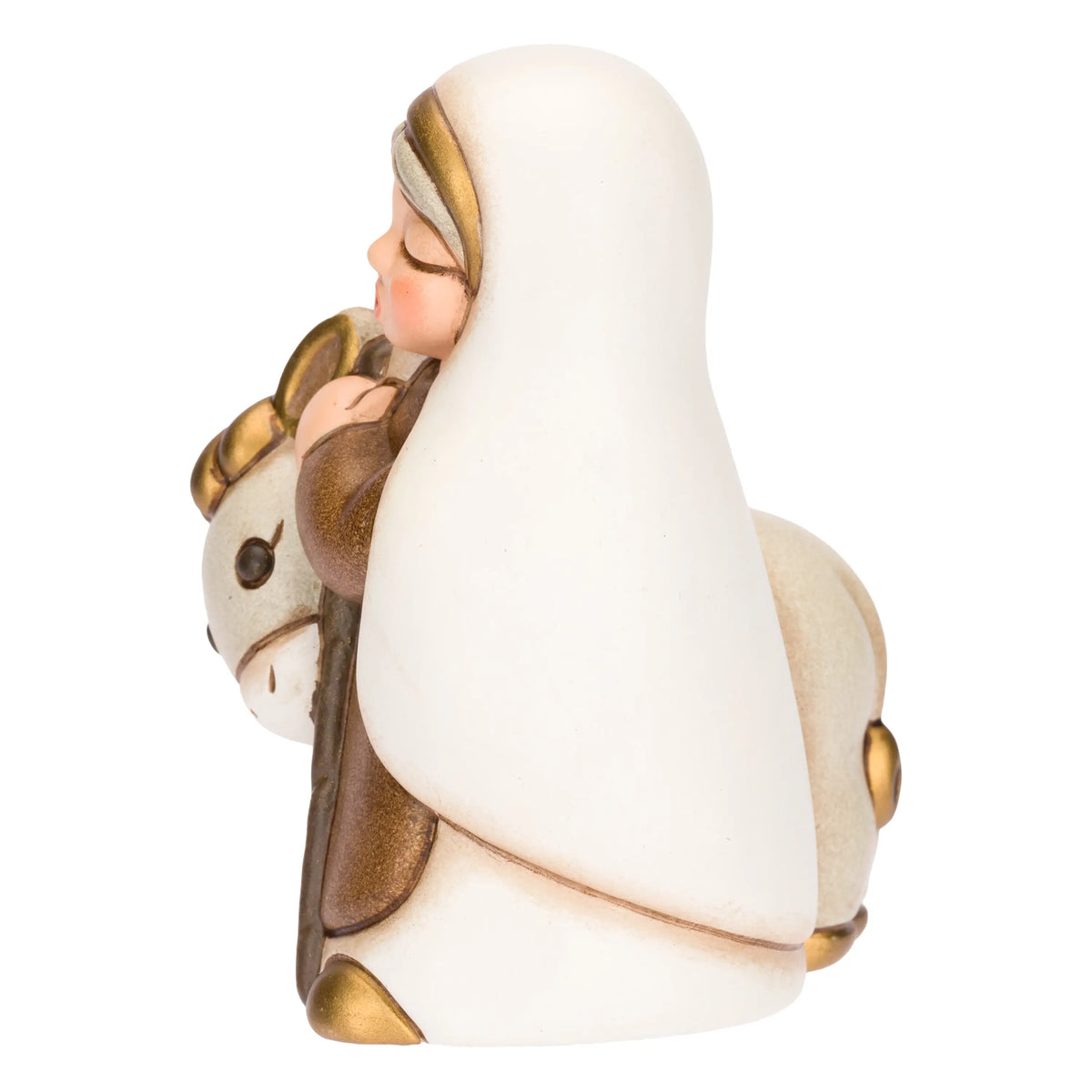 Statuina in ceramica raffigurante una donna del presepe con velo bianco e veste marrone, che accompagna un asinello con basto dorato appoggiando la mano sulla sua testa. Personaggio dal design classico e curato firmato THUN, ideale per arricchire il presepe o come idea regalo natalizia.