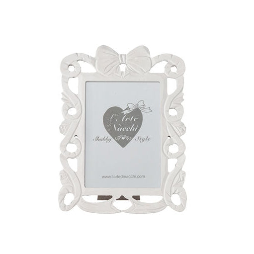 
Cornice portafoto rettangolare del marchio L'arte dei nacchi realizzata in resina bianca con una ricca lavorazione traforata in stile shabby chic lungo tutto il perimetro. Il design è caratterizzato da volute decorative e fregi ornamentali culminanti in un elegante fiocco centrale posto sulla parte superiore della cornice. Questo complemento d’arredo è ideale per esporre fotografie in ambienti dal gusto classico e romantico o come raffinata idea regalo per cerimonie ed eventi speciali.