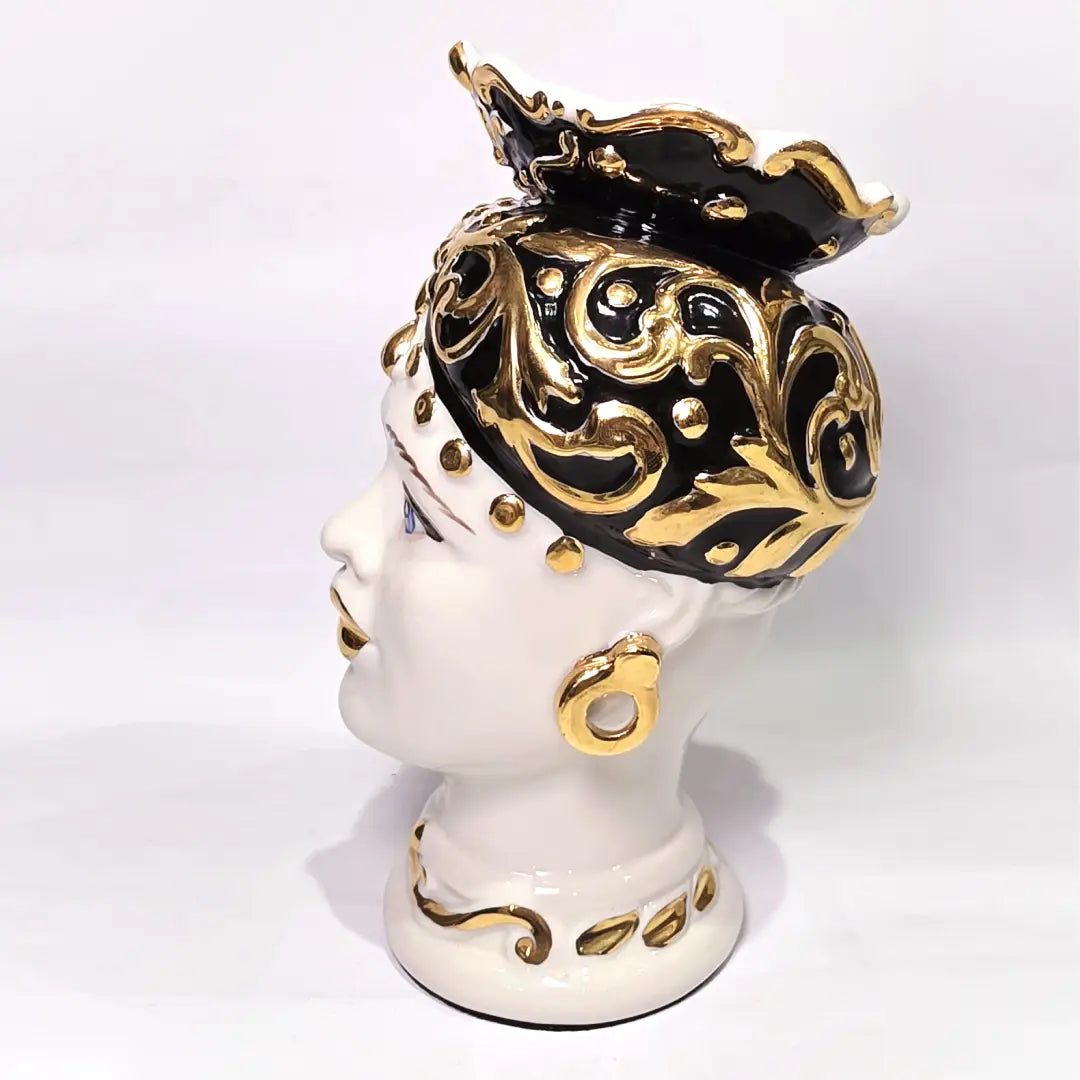 Coppia di Teste di Moro in ceramica artigianale bianca lucida con turbanti neri riccamente decorati da fregi e dettagli in oro zecchino. Queste sculture ornamentali raffiguranti un uomo con baffi e una donna con labbra dorate sono complementi d'arredo di lusso che reinterpretano la tradizione siciliana in chiave moderna ed elegante.